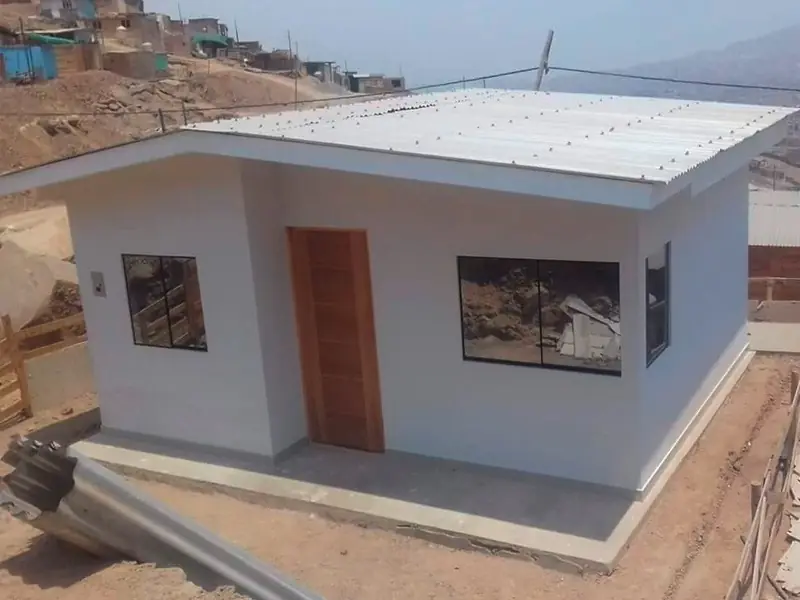 Casa de drywall de un piso terminada, con puerta y ventanas, sobre un terreno en cerro