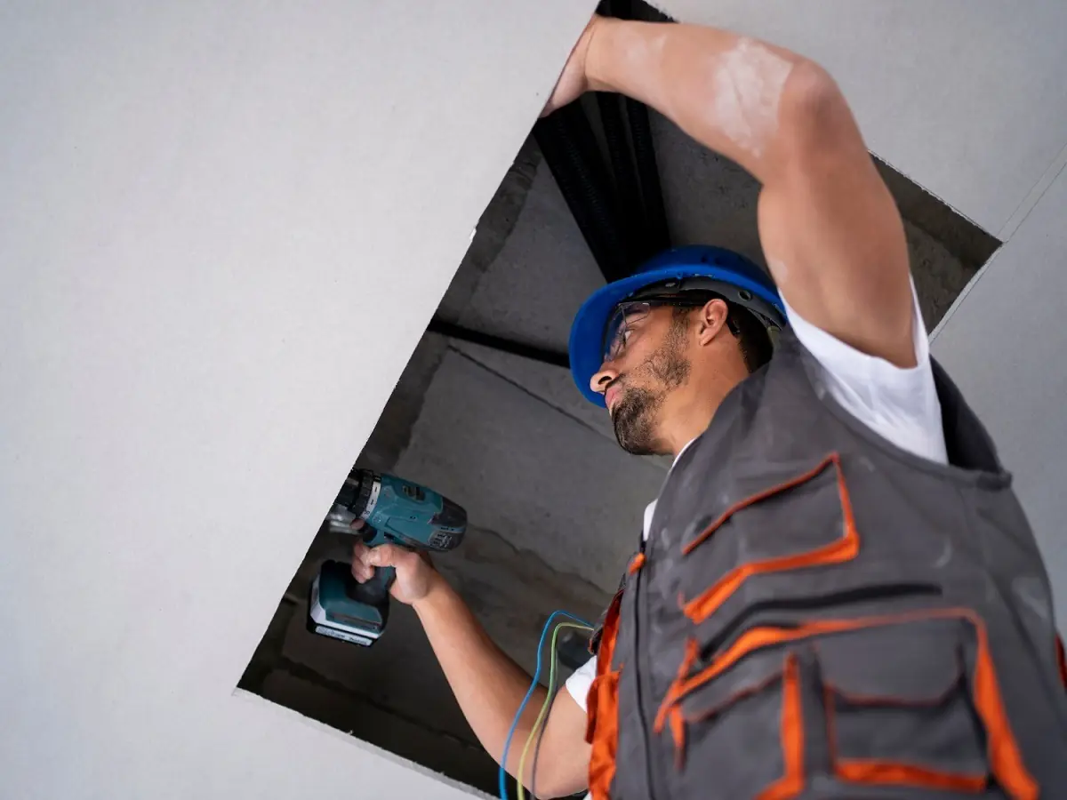 Instalador con taladro atornillando el cielo raso de drywall, referencial para Callao
