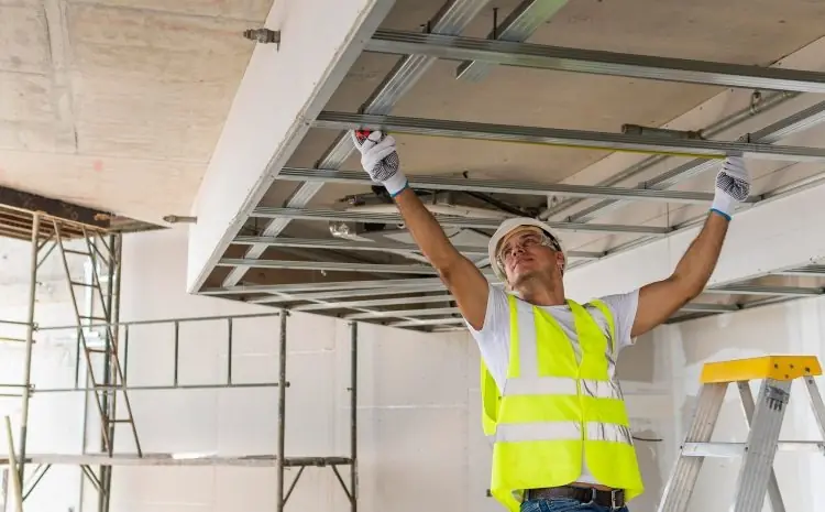 Instalador con chaleco revisando la estructura metálica de un cielo raso, referencial para Comas
