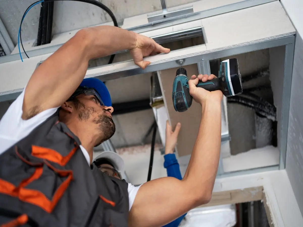 Instaladores fijando con taladro una placa de drywall en el techo